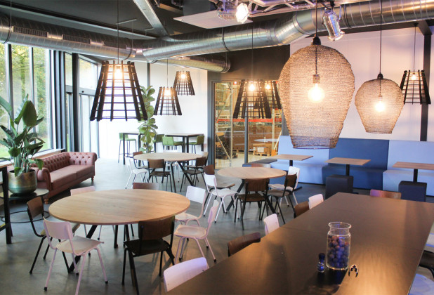 moderne kantine met ronde tafels, treinbanken en houten stoelen