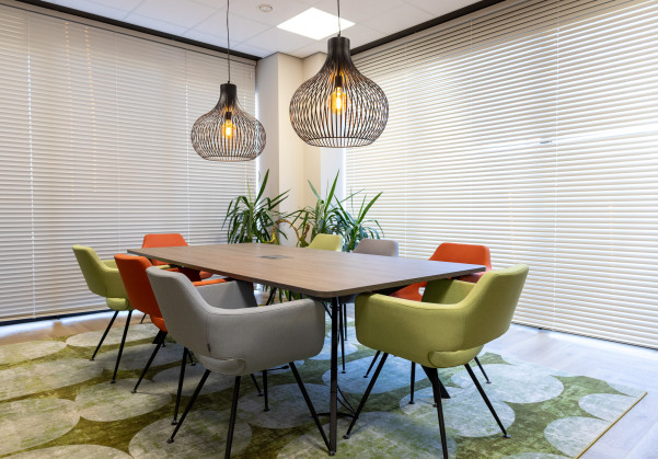 Een moderne vergaderzaal met comfortabele gekleurde stoelen en een vloerkleed