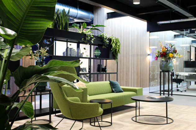 Moderne ontvangstruimte met planten en groene bank en fauteuil